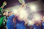 Soccer team celebrating with trophy on field