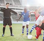 Referee whistling at soccer players on field