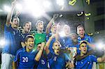 Soccer team celebrating with trophy on field