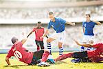 Soccer players sliding on field