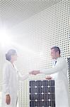 Scientists handshaking at solar panel in laboratory