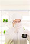 Scientist in clean suit with beaker in laboratory