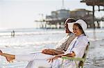 Couple relaxing in lawn chairs on beach