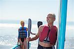 Senior couple with paddleboards on beach