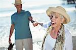 Enthusiastic senior couple holding hands on sunny beach