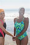 Portrait of happy lesbian couple holding hands on beach