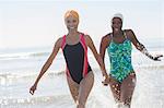 Playful lesbian couple splashing in ocean surf