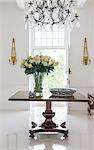 Chandelier over bouquet on table in luxury foyer