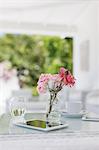 Pink roses on patio table next to coffee cup and digital tablet