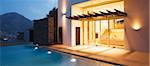 Illuminated modern house overlooking swimming pool
