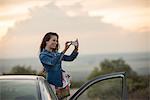 Young woman taking picture with her phone, Mineral de Pozos, Guanajuato, Mexico, North America