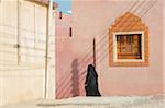 Muslim Woman in Burqua and Hijab Walking passed Typical Omani House Window, Al Ashkharah, Oman