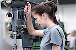 Female engineer using machine in workshop