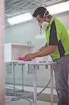 Man spraying wooden box in carpenters workshop