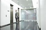 Businessman waiting for elevator in office corridor