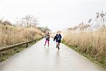 Young sister and brother running along rural road