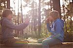 Twin brothers taking photographs on smartphone in forest