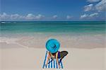 Young woman relaxing on beach with blue sunhat