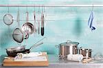 Assorted kitchen utensils on a stainless steel unit and hanging on a metal rod