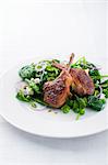 Lamb chops on a spinach salad with peas, onions and feta