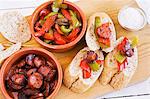 Peppers with chorizo and bread on a wooden board (Spain)