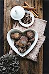 Chocolate and cinnamon treats in a heart-shaped bowl, grated chocolate, cinnamon sticks