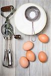 An old rotary hand whisk, eggs and sugar