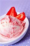 A scoop of frozen yoghurt with strawberries in a shallow dish