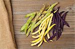 Wax beans, scarlet runner beans and blue French beans on a wooden table