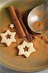Star-shaped biscuits, ground cinnamon, cinnamon sticks and a spoon