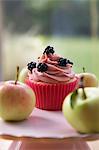 Cupcake with blackberries, surrounded by fresh apples