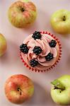 Cupcake with blackberries, surrounded by fresh apples