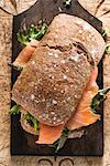 A smoked salmon and lettuce sandwich on a chopping board