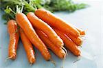 Fresh carrots on a pale blue surface (close-up)