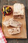 Pâté with chicken liver, partly sliced, and a small bowl of pickled gherkins