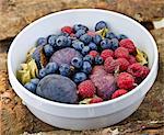 A fruit bowl with figs, blueberries and raspberries on a wooden surface