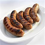 Five grilled Bratwurst on White Serving Platter on White Background