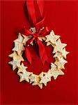 Wreath made of star cookies with a red ribbon in front of a red background