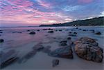 Long exposure of a pink sunset at the beach during dusk with rocks in the foreground, Tangalle, Sri Lanka, Asia