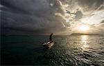 A man in a dug out canoe at sunset, Solomon Islands, Pacific