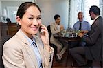 Businesswoman using cellphone with colleagues having meal