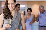 Businesswoman holding champagne flute with colleagues in background