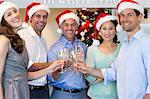 People in Santas hats toasting champagne flutes at bar