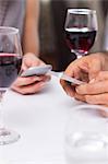 Mid section of a couple with wine glass text messaging