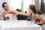 Couple with wine glass and cellphone arguing in restaurant