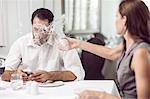 Woman throwing water on man in restaurant