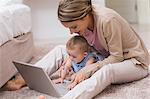 Mother teaching baby to use laptop