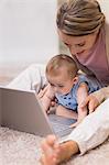 Beautiful mother teaching baby to use laptop