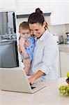 Mother using laptop while carrying baby at counter