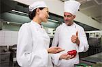 Chef teaching trainee how to slice vegetables